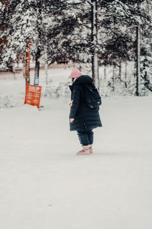 Girl in pink hat and black coat in snow in Rovaniemi, Lapland in winterの写真素材
