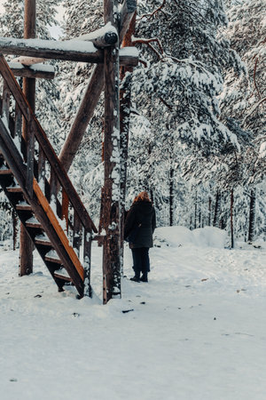Woman stood in snow next to lookout tower in Ounasvaara in Rovaniemi, Laplandの写真素材