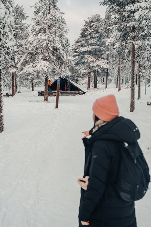 Woman looking at snowy laavu in Ounasvaara forest in Rovaniemi, Laplandの写真素材