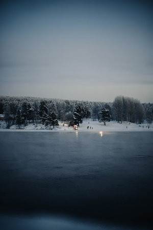 Sauna lights across Ounasjoki river in polar night in Rovaniemi, Laplandの写真素材