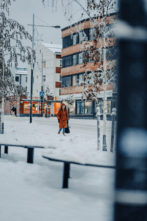 Woman walking down snowy road, street photography in Rovaniemi, Laplandの写真素材