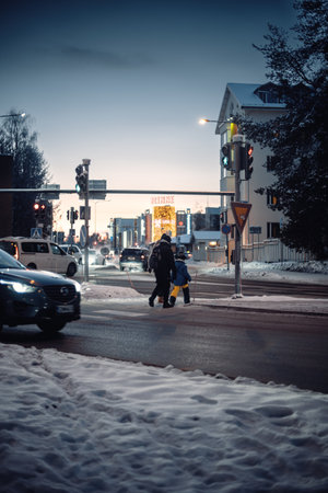 Tourists crossing busy road in Rovaniemi center in snowy winter in Laplandの写真素材