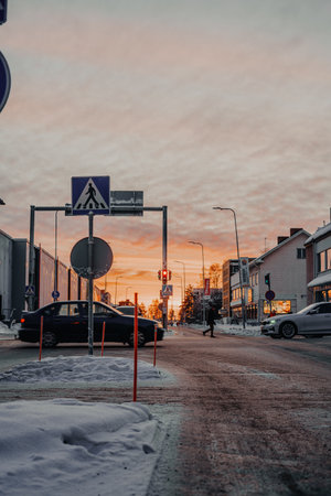 Golden hour over pedestrian crossing of snowy road in Rovaniemi, Laplandの写真素材
