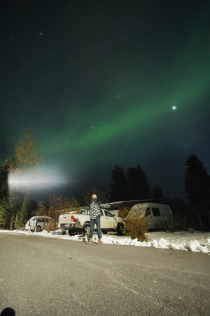 Man stood under northern lights on street in Rovaniemi, Laplandの写真素材
