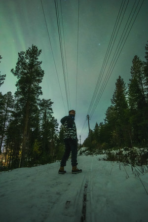 Man in snow at night in Rovaniemi, Lapland under auroraの写真素材