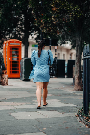 Woman in sky blue dress walking down pavement in London, UKの写真素材