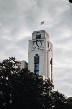 Church tower with clock and union jack flag in front of clouds in London, UKの写真素材