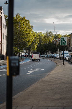 Van driving down street past trees in London, UKの写真素材