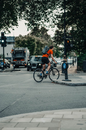 Man cycling across road in orange t-shirt in London, UKの写真素材