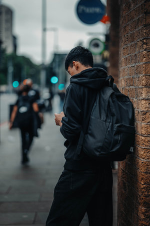 Man with black backpack leaning against wall in London, UKの写真素材