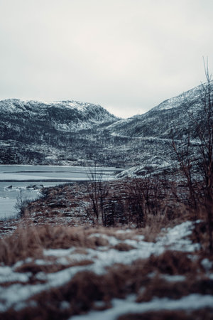 Road into snowy mountains by frozen fjord in the arctic near Tromso, Norway