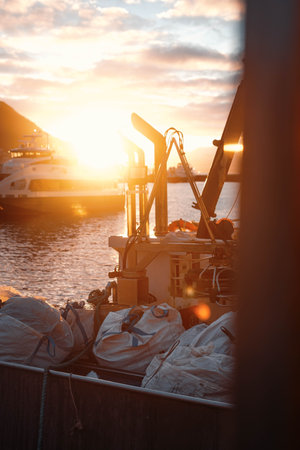 Golden hour sunlight in the arctic over a fishing boat at Tromso harbour, Norwayの写真素材