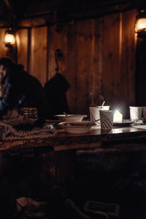Hot drinks and reindeer soup on table in wooden Saami hut near Tromso, Norwayの写真素材