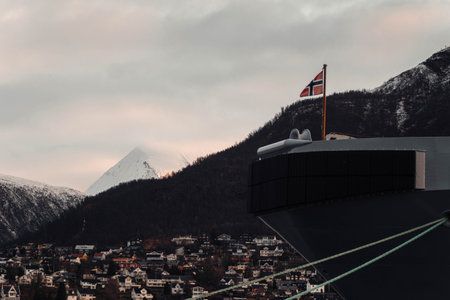 Snowy arctic mountain behind flag on big ship in Tromso harbourの写真素材