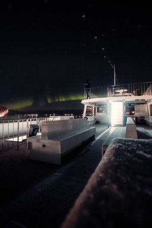 Aurora borealis over the front of arctic fjord cruise ship in Tromso, Norwayの写真素材