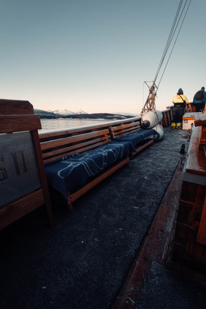 Benches with blue blankets on wooden fishing boat in Tromso, Norway