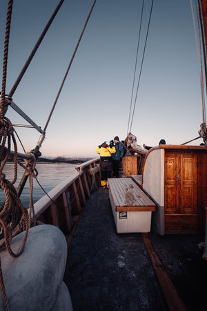 People on wooden fishing boat tour on fjord in Tromso, Norway