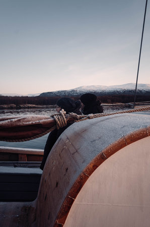 People looking over arctic fjord at sunset from wooden boat in Tromso, Norway