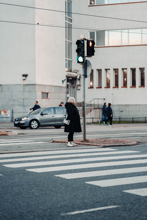Woman in black coat waiting to cross road in the center of Helsinki, Finlandの写真素材