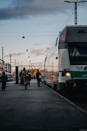 People walking in Helsinki central train station at sunset next to trainの写真素材