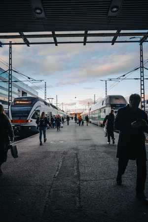 People on platform between trains in Helsinki central train station at sunsetの写真素材