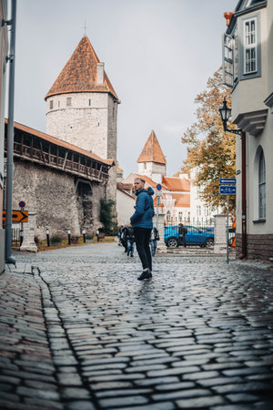 Man walking towards old town city wall in Tallinn, Estonia in autumnの写真素材