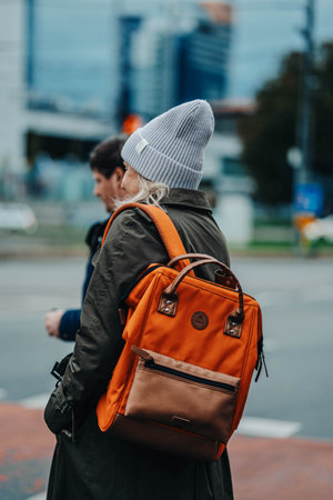 Woman with orange backpack waiting to cross road in Tallinn, Estoniaの写真素材