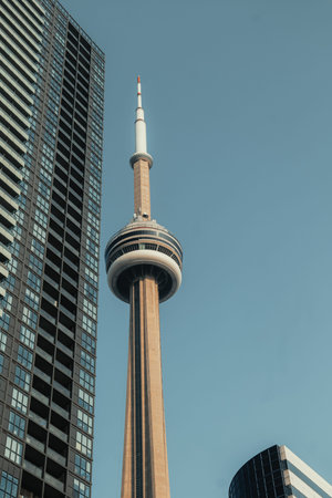 CN Tower behind office block in blue sunny sky in Toronto, Ontario