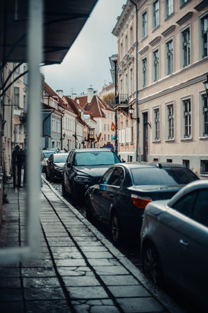 Cars parked on old town street in autumn in Tallinn, Estoniaの写真素材
