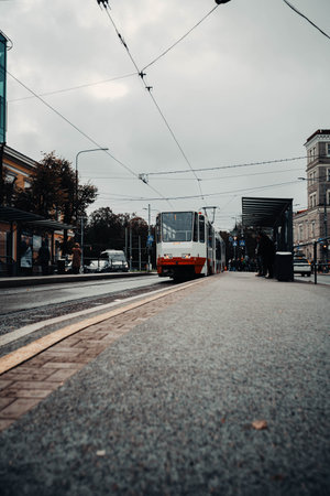 Tram about to leave station in street on cloudy autumn dayの写真素材