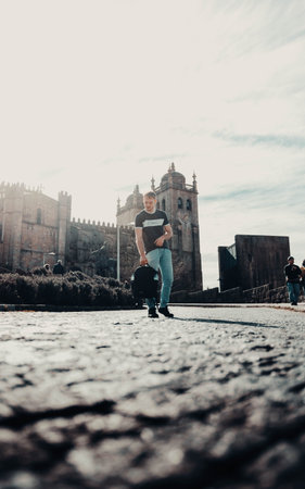 Man holding bag in front of Cathedral of Porto, Portugal