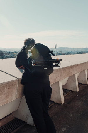 Man looking over Porto, Portugal leaning on wall with black backpack