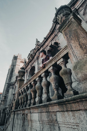 Man leaning over railings of the Cathedral of Porto, Portugalの写真素材