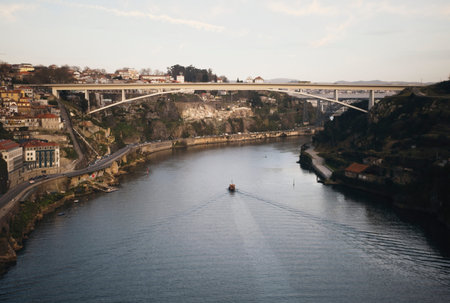 Landscape shot of boat about to sail under bridge, River Douro in Porto Portugal