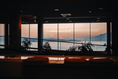 Sunset view from an indoor area with large windows overlooking the seaの写真素材