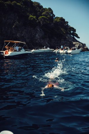 Man swimming in the sea by boats and the Croatian coastline near Dubrovnikの写真素材