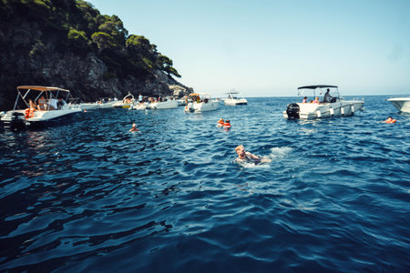 People swimming in the sea between boats outside Dubrovnik, Croatia in summer
