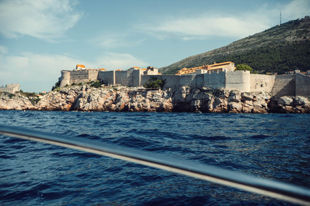 Dubrovnik, Croatia old town city wall on rocky coastline, shot from boat on seaの写真素材