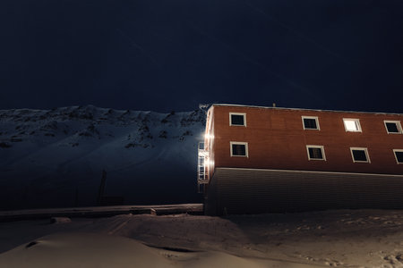 Wooden cabin below snowy arctic mountain in Longyearbyen, Svalbardの写真素材