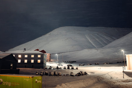 Snowmobiles parked outside buildings under mountain in Longyearbyen, Svalbard