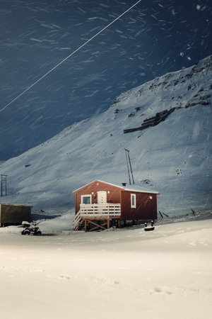 Snowing on wooden cabin under mountain in Longyearbyen, Svalbardの写真素材