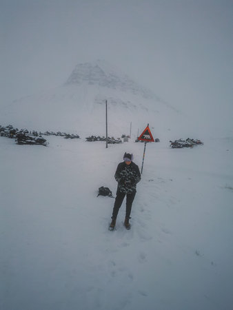 Man stood in front of Sarkofagen polar bear sign in Longyearbyen, Svalbard