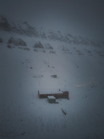 Foggy drone shot of building under snowy mountain in Longyearbyen, Svalbardの写真素材