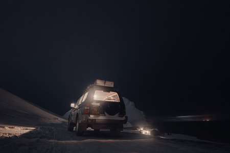 Car parked in the snow at night in front of Bjorndalen, Longyearbyen, Svalbardの写真素材