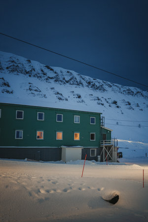 Green building in front of snowy mountains in Longyearbyen, Svalbard in winterの写真素材