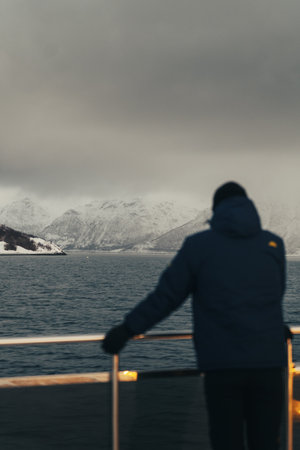 Man looking at snowy Lyngen Alps on overcast arctic day, northern Norwayの写真素材