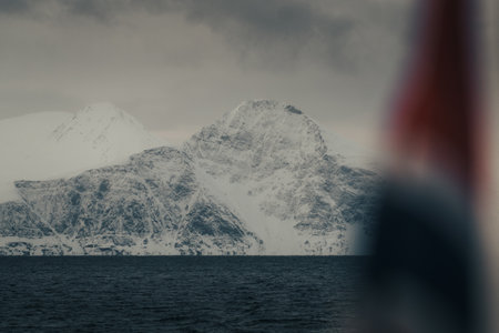 Snowy mountain behind Norwegian flag in the arctic Lyngen Alps in Norway, winterの写真素材