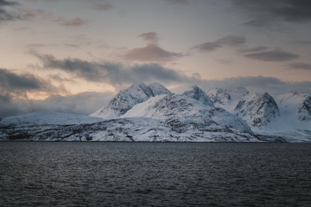 Landscape shot of snowy Lyngen Alps mountains by arctic ocean, northern Norwayの写真素材