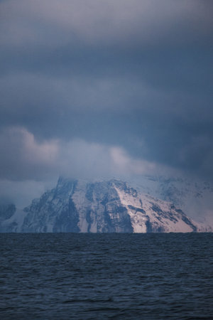 Distant rocky snowy mountains under grey clouds, the Lyngen Alps, arctic Norwayの写真素材
