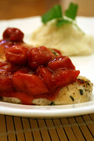 Cherry topped chicken with a side of mashed potatoesの写真素材